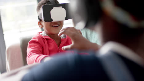 African-american-sister-and-brother-using-vr-headset-in-living-room,-slow-motion