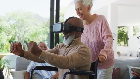 happy senior diverse people with man in wheelchair using vr headset at retirement home