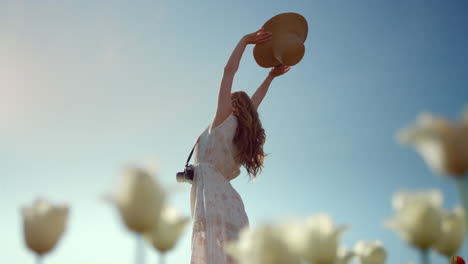 unknown woman silhouette with sunhat stretching hands to blue sky in sunny day.