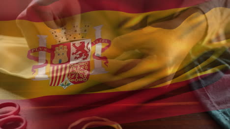 spanish flag waving against mid section of woman sewing face mask