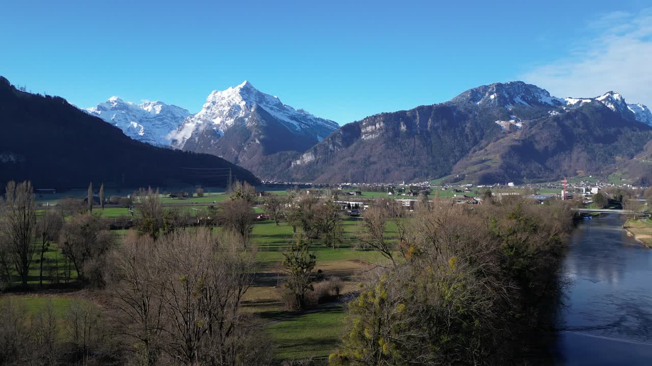 clip de avión no tripulado que muestra pintorescas montañas nevadas y tierras bajas cubiertas de hierba en los alpes