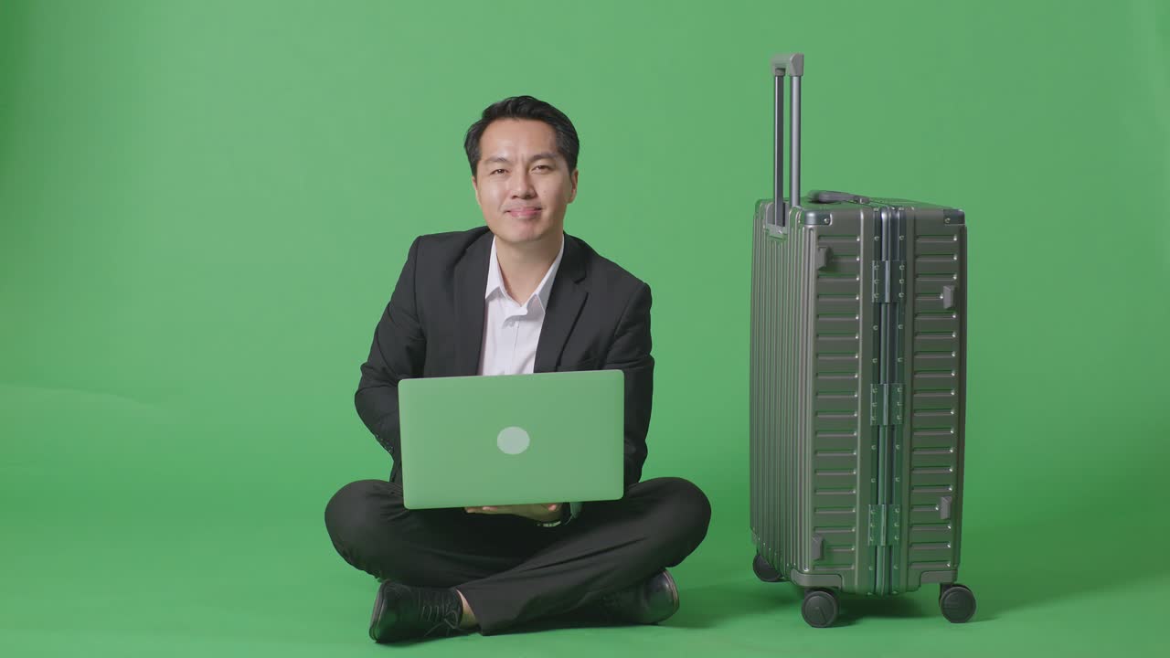 녹색 화면 배경 스튜디오에 앉아있는 동안 노트북을 사용하는 짐과 함께 아시아 사업가 여행자의 몸이 가득 차 있습니다.