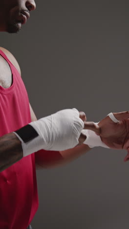 video vertical de primer plano de un boxeador masculino envolviendo las manos con vendajes protectores antes de un partido de boxeo o una sesión de entrenamiento 1