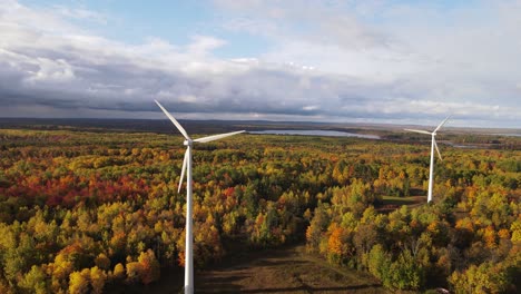 stormy clouds coming over wind turbines and autumn colored forest, aerial view