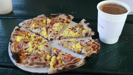 vista de una pizza y café de desayuno horneados con leña en rodajas