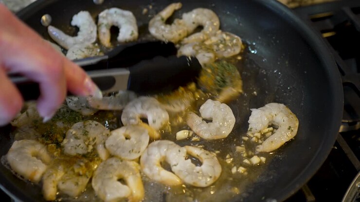 Sauteing shrimp in butter and herbs in a frying pan