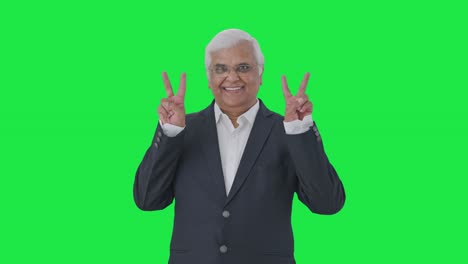 Happy-Indian-senior-journalist-showing-victory-sign-Green-screen