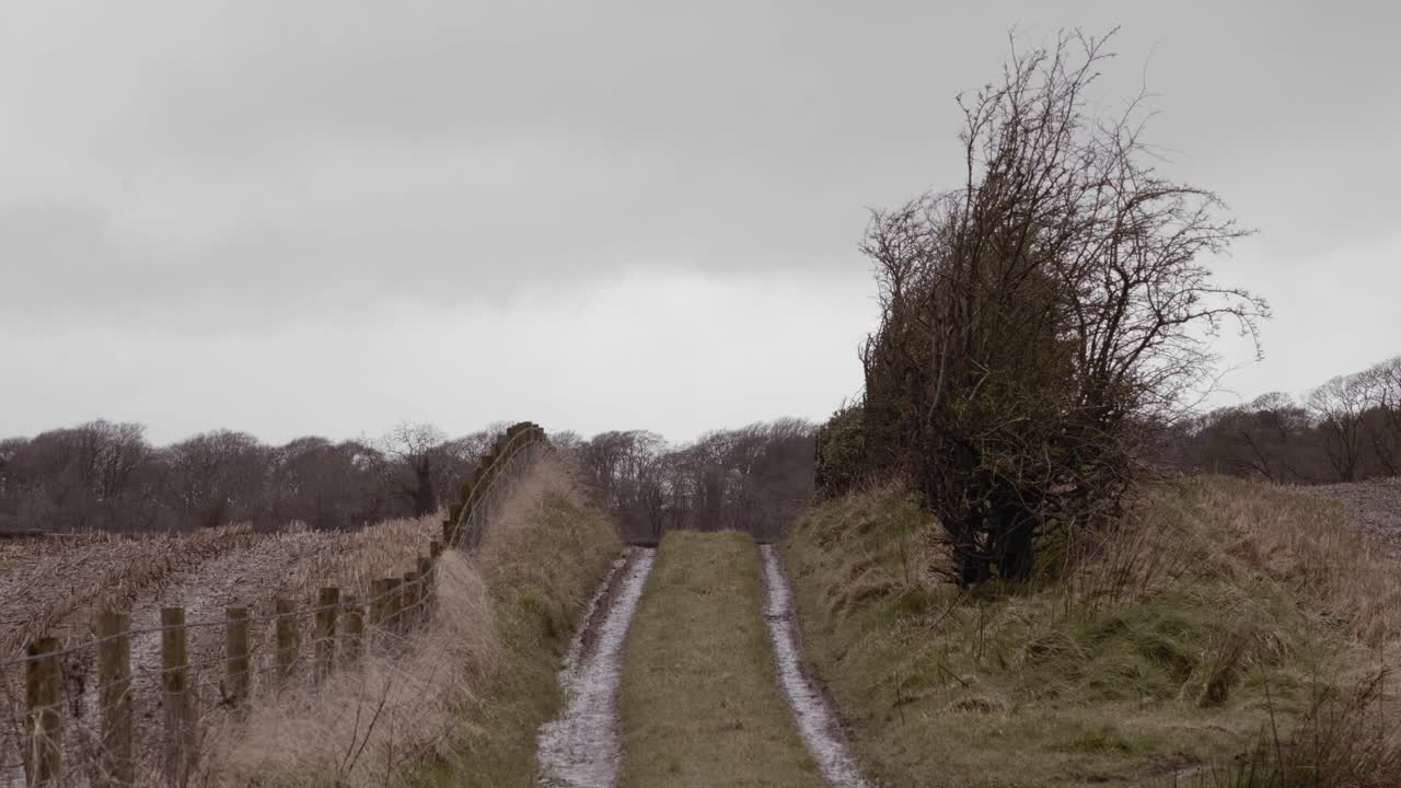 Rural country lane dirt track over farmland hill on winter day, still shot