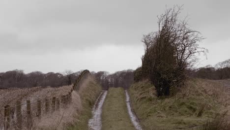 rural country lane dirt track over farmland hill on winter day, still shot