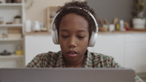 niño estudiando en una computadora portátil con auriculares