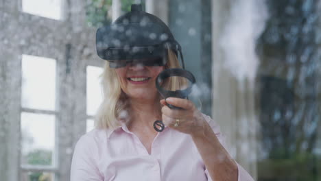 Blick-Durch-Das-Fenster,-Während-Eine-Reife-Frau-Ein-Virtual-Reality-Headset-Trägt-Und-Gaming-Controller-In-Der-Hand-Hält