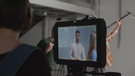 female film director and assistant watching actors shooting movie or video in studio on monitor 6