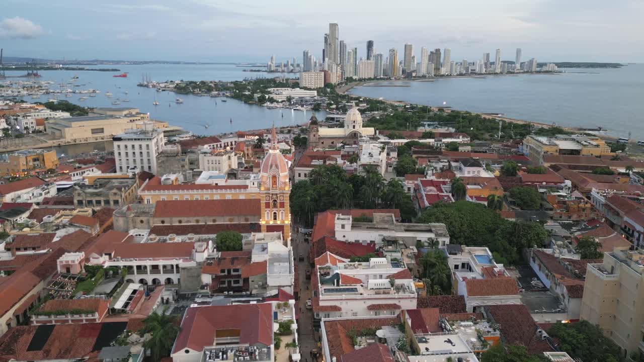Drohnenflug über Cartagenas ummauerte Altstadt mit moderner Skyline in der Ferne von Bocagrande, im Kontrast zur alten Kirchturmspitze.