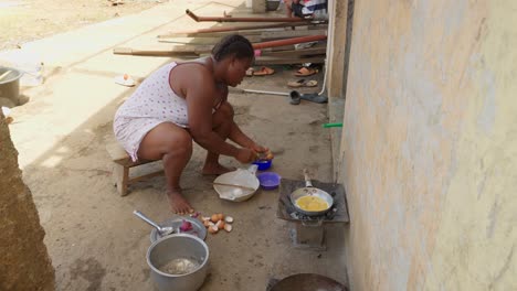 ghanaian cooking, preparing egg omelette on a charcoal stove to accompany banku, typical african food