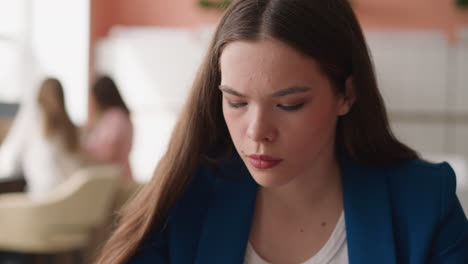 focused woman looks downward in library premise. young lady concentrates on reading sitting in university information center. reading woman closeup