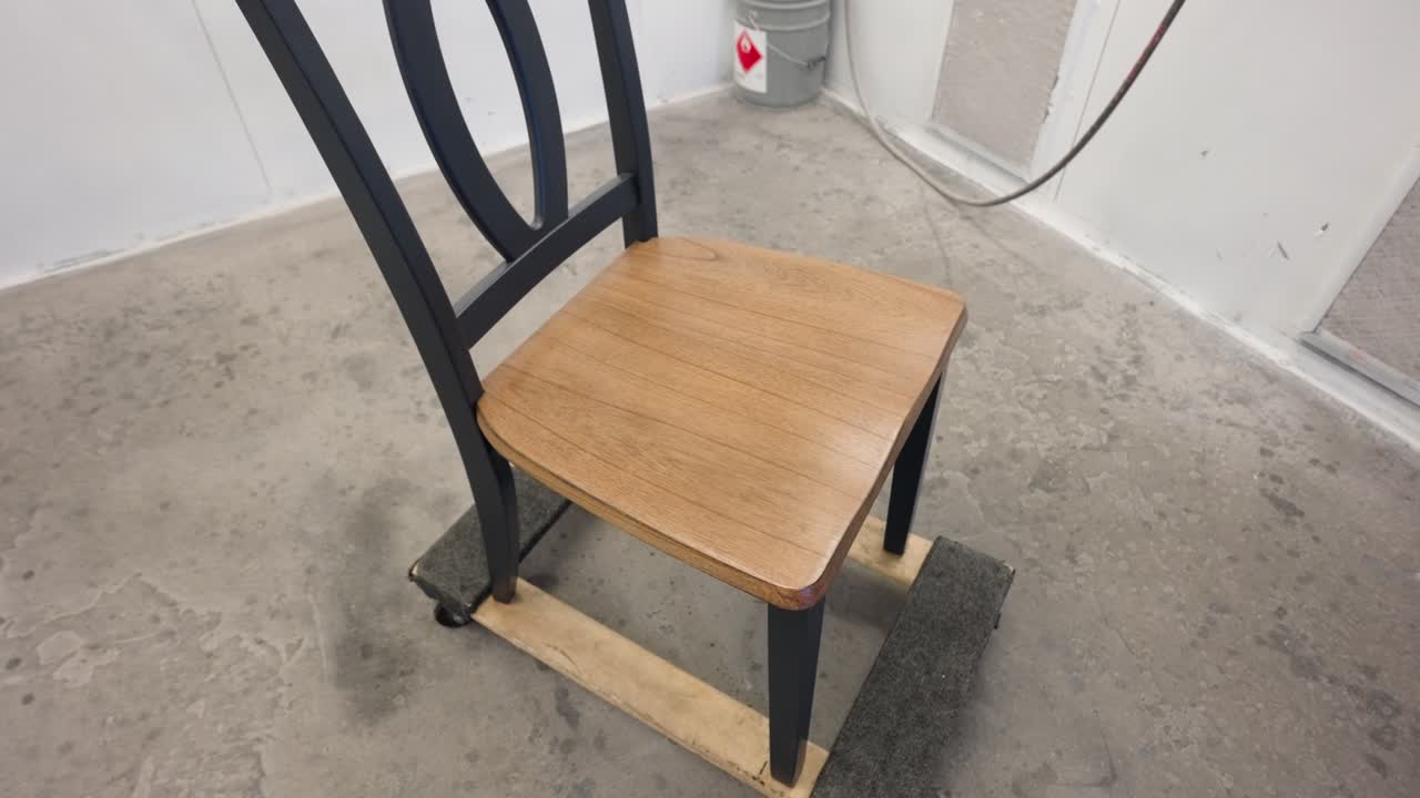 Camera moves around dining chair with natural wood seat in spray enclosure