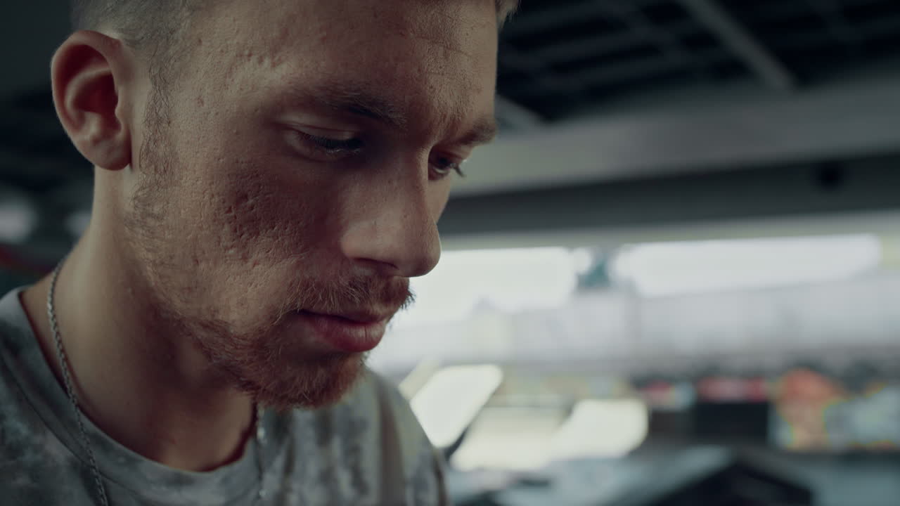 Attractive man reading news on mobile phone at skate park. Portrait focused teen
