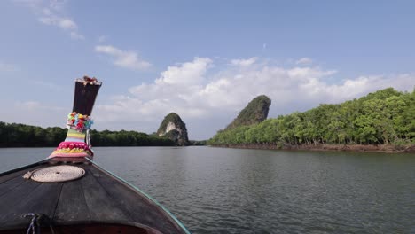 cámara panorámica a la derecha de un bote tailandés de madera decorado con flores de colores que navega río abajo durante la puesta de sol una playa de arena blanca y un bosque de manglares a ambos lados en la ciudad de krabi, tailandia