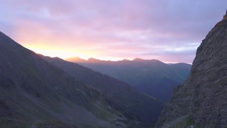 Stunning-sunset-sky-filled-with-pink-and-purple-over-rugged-mountain-terrain-of-Romania-and-Negoiu-Peak