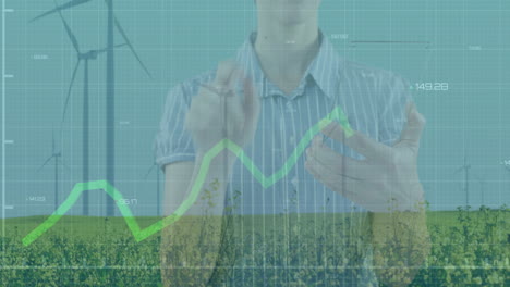 woman gesturing with virtual chart overlay in farm tech, showing green line graph and wind turbines