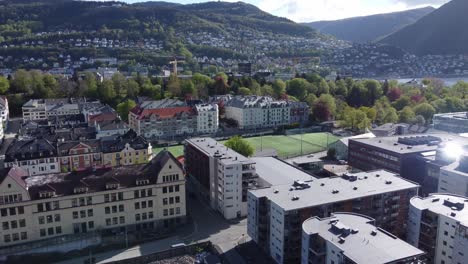 arstad and kronstad at danmarksplass aerial - buildings and soccer field in center with solar flare on building - aerial with landas in background - bergen norway