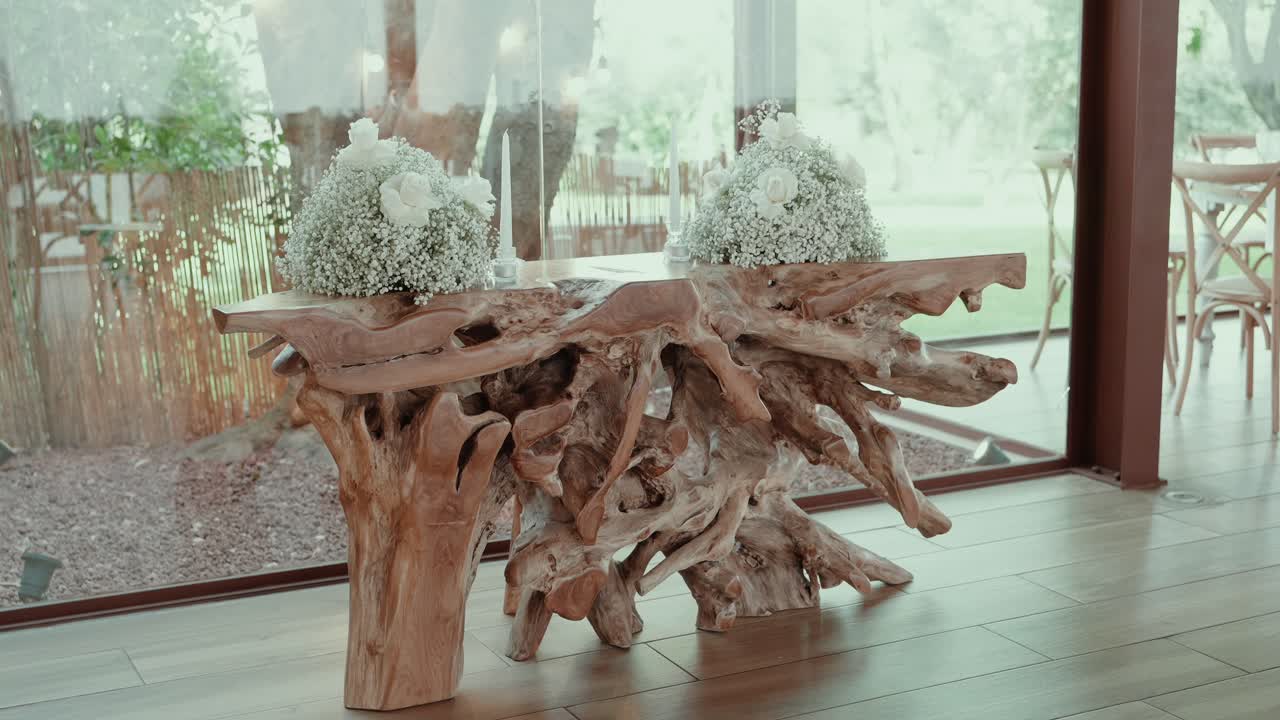 Natural wood root table decorated with white roses and baby's breath wedding arrangement