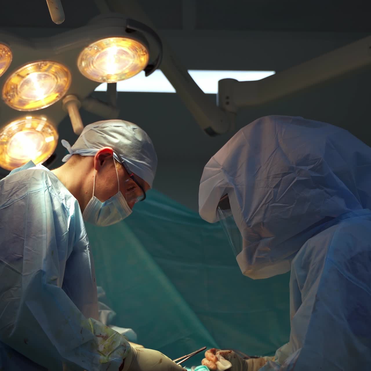 Surgeons in protective uniform. Medical specialists perform a surgery in the operating room. Surgical concept.