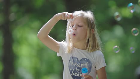 una alegre joven rubia se sumerge en el juego al aire libre, creando burbujas de jabón que bailan a la luz del sol
