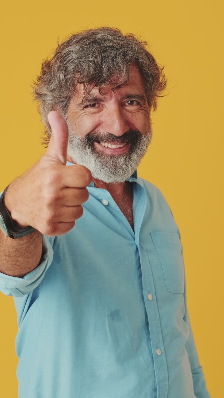 Mature Man Points and Gives Thumbs Up with a Smile