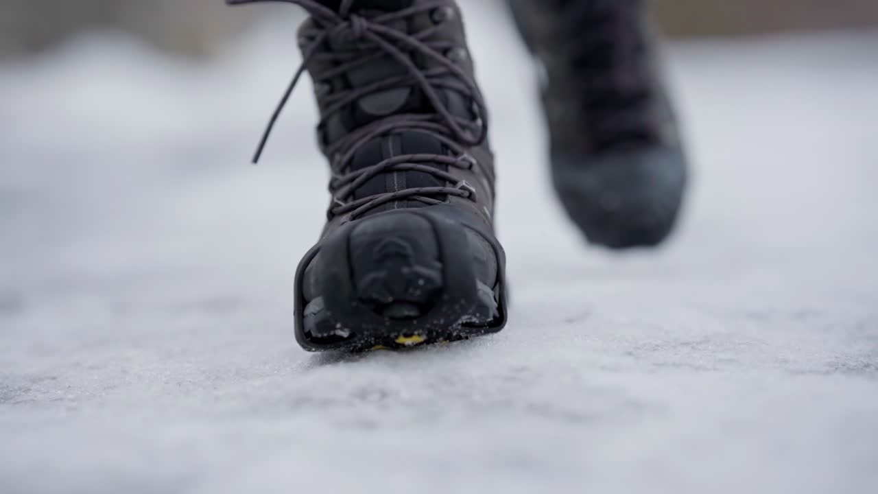 Kaki berjalan menuju kamera dengan paku anti-selip di sepatu, gerakan lambat close-up genggam