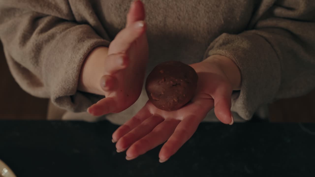 Slow motion hands shape chocolate cookie dough into round ball