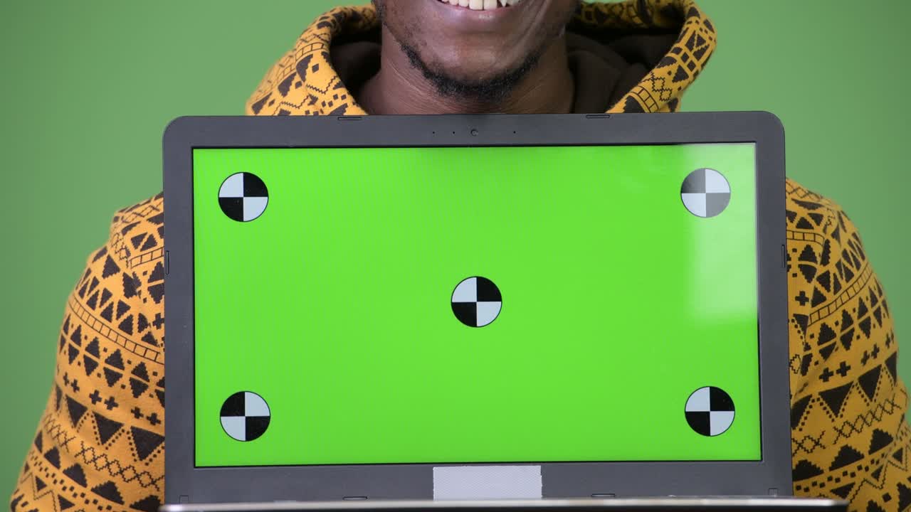 Jovem homem africano bonito mostrando laptop