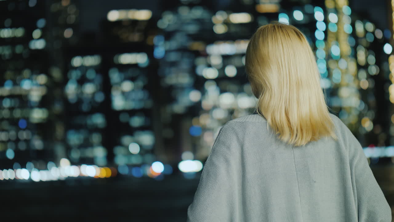 mujer rubia mirando la vista trasera de la ciudad nocturna