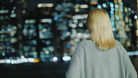 mujer rubia mirando la vista trasera de la ciudad nocturna