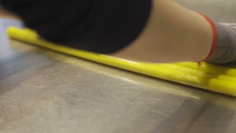 making caramel candies. hands rolling yellow candy strips