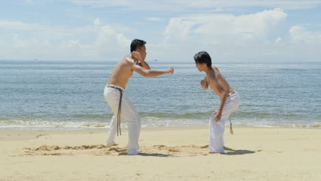 dos hombres bailando capoeira en la playa