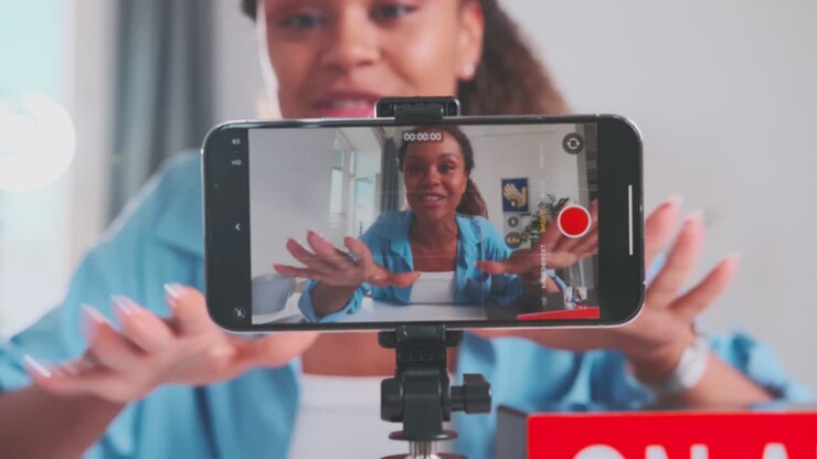 Giovane e felice donna afroamericana registra un vlog al cellulare seduta a un tavolo