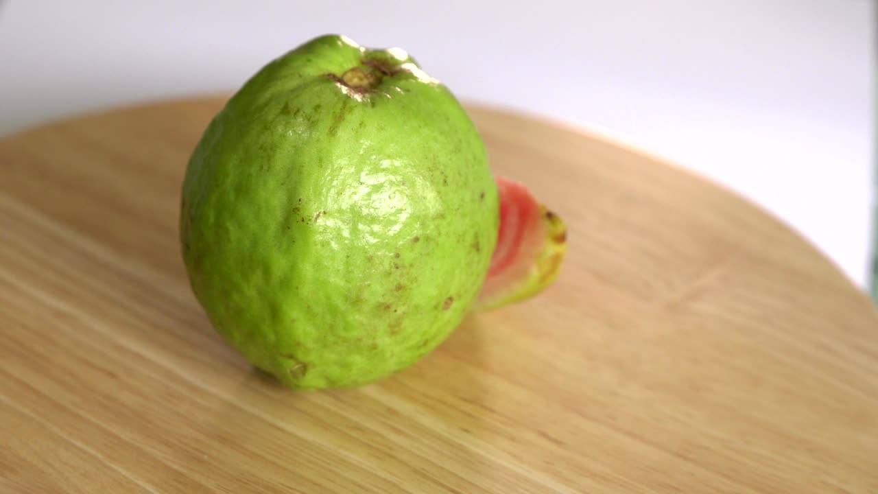 나무 테이블 과 색 배경 에 개 를 은 구아바 가 회전