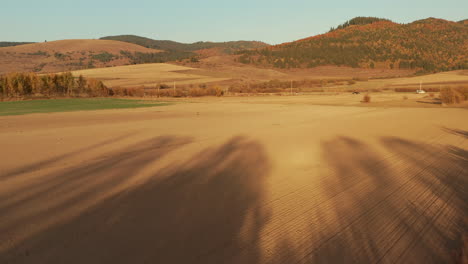 flying towards vast agricultural fields with ridges in the background during autumn