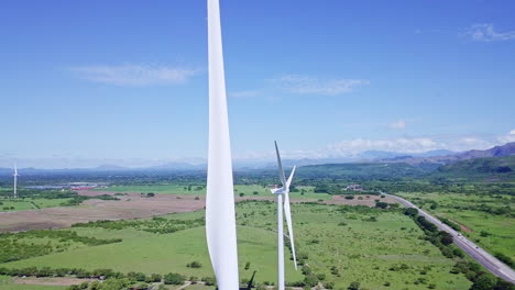 aerial-view-of-wind-turbine,-trees,-mountain,-on-sunny-day,-pan