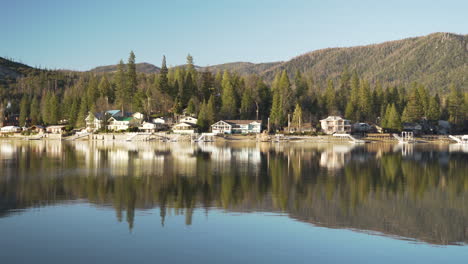 luxury homes on an alpine lake with mountain and trees in reflection of water during magic hour