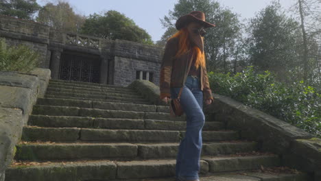 female redhead wearing plague mask descending stone stairway with follow pan into bright sunlight