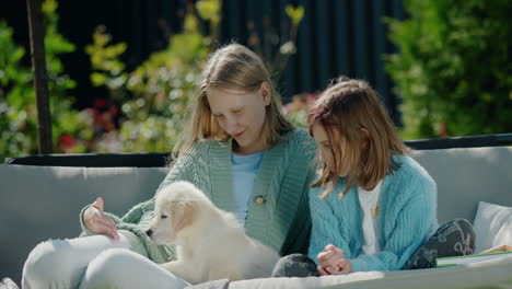 two girls playing with a puppy, sitting on a swing in the backyard of the house