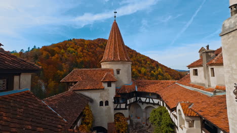 red tiling on the roofs of old bran castle in romania. mount covered with colorful forest at backdrop.