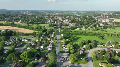 drone view of small american town in summer, showing green suburbs, open fields and a peaceful neighborhood with tree-lined streets. classic rural usa landscape. wide shot. main street in housing area