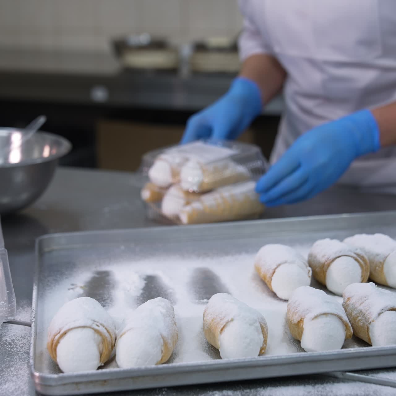 Delicious desserts packaging at the food factory. Confectionery worker puts a few cannoli cakes into plastic boxes. Close up