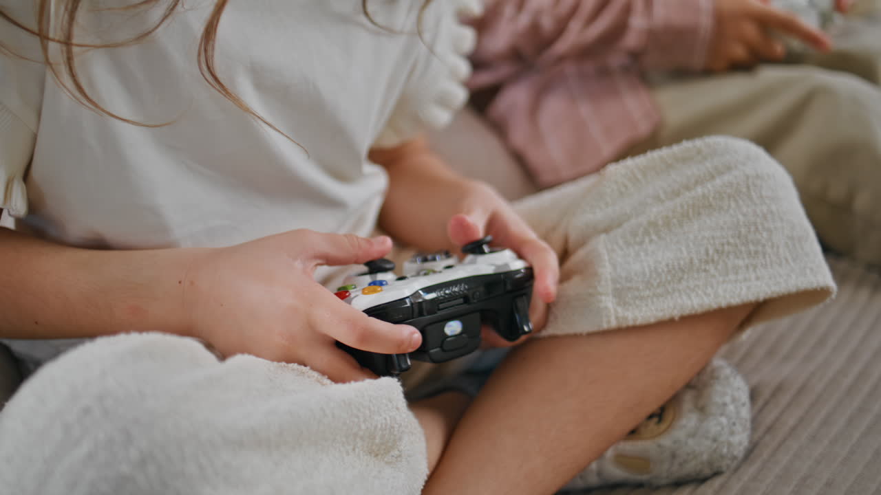 Child hands holding controller trying win at home closeup. Gamer girl playing