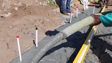 close up view of concrete being poured into foundation frame for home