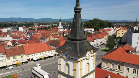 Torre-Del-Reloj-De-La-Iglesia-Del-Espíritu-Santo-Con-Edificios-De-Techo-Rojo-En-Pozega,-Ciudad-De-Slavonia,-Croacia