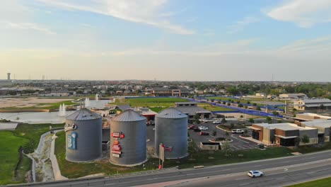 Moving-in-an-arc-quickly-to-the-left-to-show-downtown-development-that-features-3-iconic-gin-silos-as-part-of-a-downtown-development